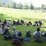 Menschen sitzen auf einer Wiese im Kreis